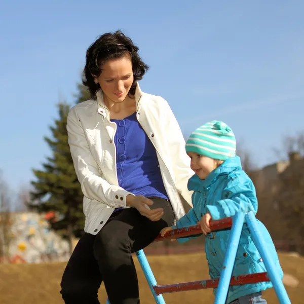 Schöne junge Mutter beim Fitnesstraining mit ihrer kleinen Tochter auf dem Spielplatz — Stockfoto