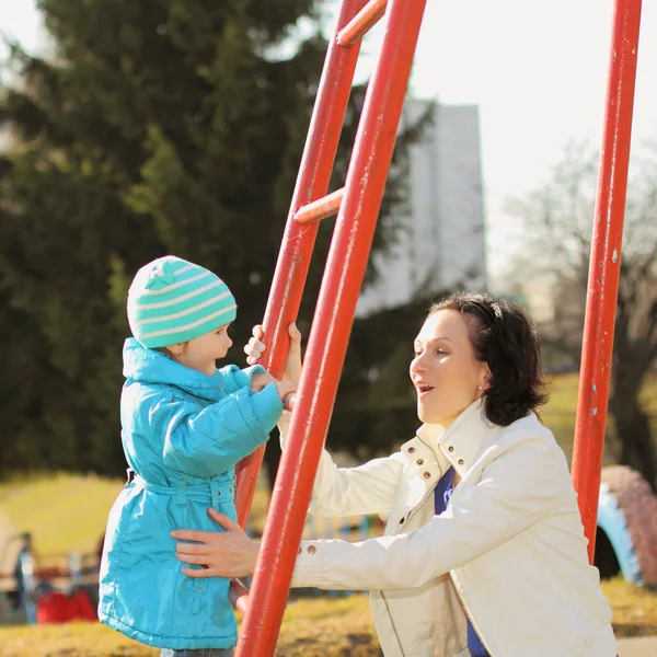 Bela jovem mãe fazendo fitness com sua filhinha no playground — Fotografia de Stock