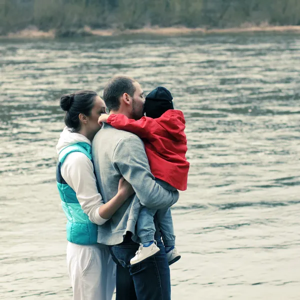 Мама, папа и ребенок на руках смотрят на реку — стоковое фото