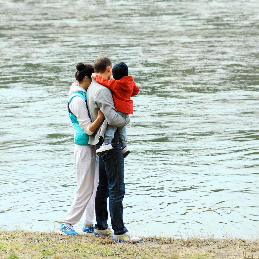 Mom, dad and baby in his arms looking at the river