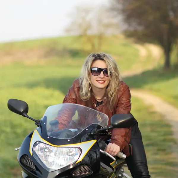 Байкерша в солнечных очках сидит на мотоцикле — стоковое фото