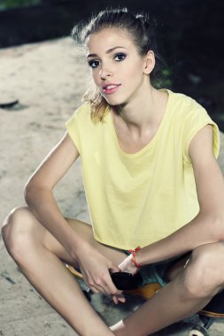 kaykay üzerinde oturan ince kız