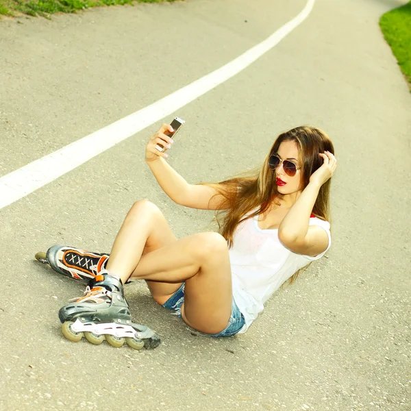 Flicka på rullskridskor sitter på vägen — Stockfoto