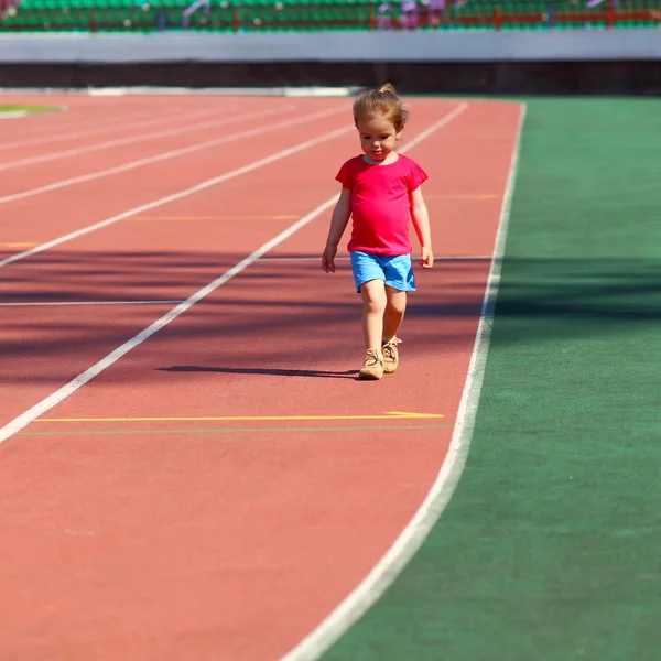 Liten flicka kör på stadion — Stockfoto