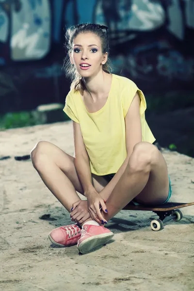 Slim girl sitting on skateboard — Stock Photo, Image