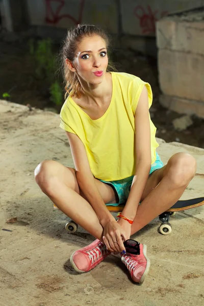 Стройная девушка сидит на скейтборде — стоковое фото