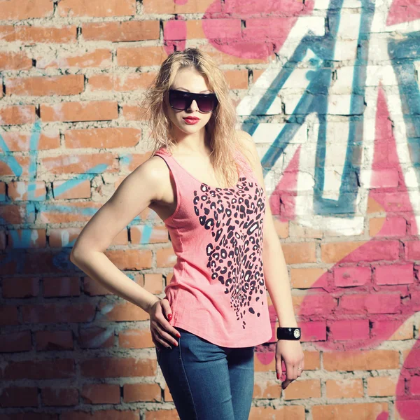 Fashionable girl against brick wall — Stock Photo, Image