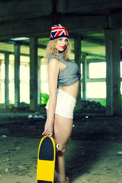 Fille avec planche à roulettes dans garage abandonné — Photo