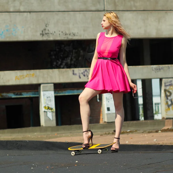 Девушка на высоких каблуках со скейтбордом — стоковое фото
