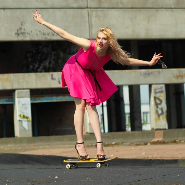 Mooi meisje op een skateboard op het dak — Stockfoto