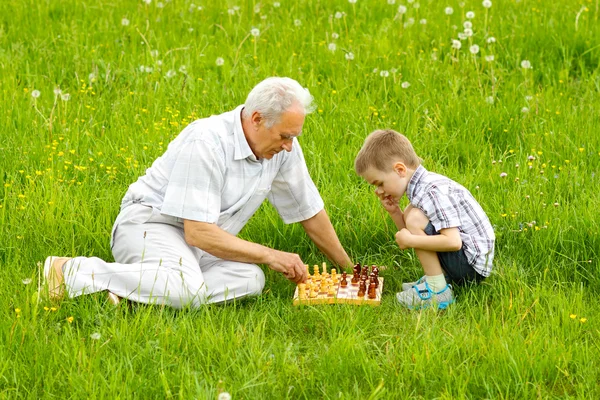 Farfar och barnbarn spelar schack Stockbild