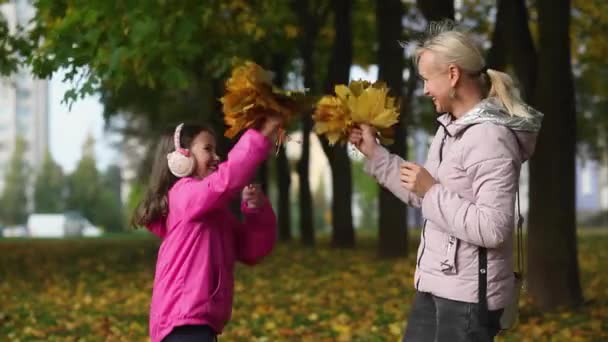 Mam en dochtertje spelen in het park met gele bladeren. — Stockvideo