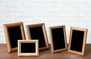 Ahşap masadaki eski fotoğraf çerçeveleri, beyaz tuğla duvar