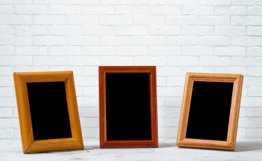 Ahşap masadaki eski fotoğraf çerçeveleri, beyaz tuğla duvar