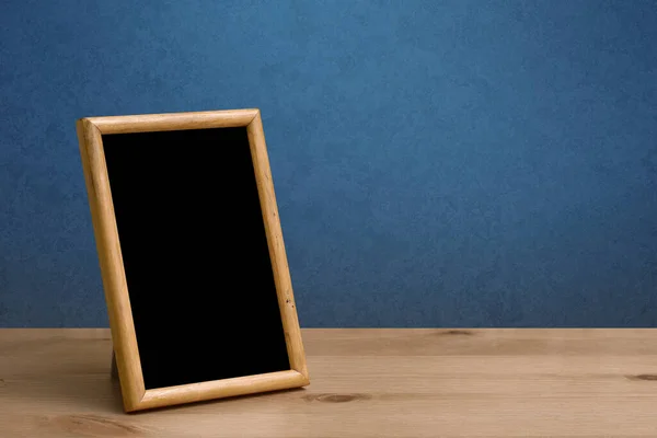 木製のテーブルの上の写真フレーム青い壁 — ストック写真