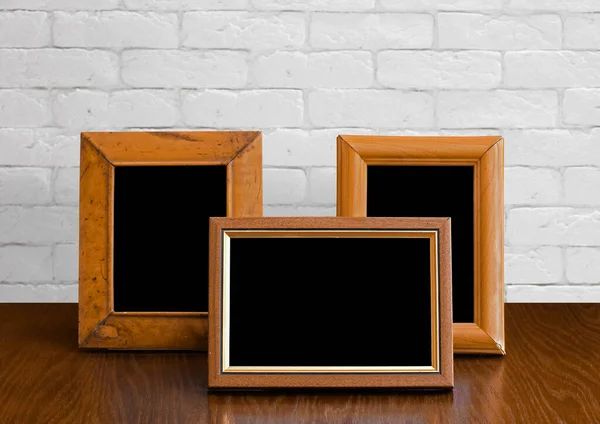 Oude Fotolijstjes Houten Tafel Witte Bakstenen Muur — Stockfoto