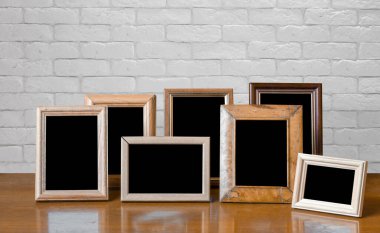 Ahşap masadaki eski fotoğraf çerçeveleri, beyaz tuğla duvar
