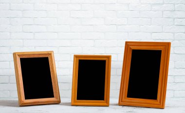 Ahşap masadaki eski fotoğraf çerçeveleri, beyaz tuğla duvar