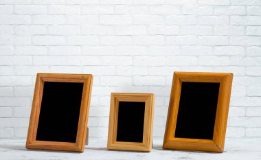 Ahşap masadaki eski fotoğraf çerçeveleri, beyaz tuğla duvar