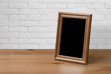 Tahta masadaki eski fotoğraf çerçevesi, beyaz tuğla duvar.
