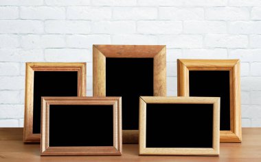 Ahşap masadaki eski fotoğraf çerçeveleri, beyaz tuğla duvar