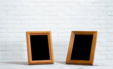Ahşap masadaki eski fotoğraf çerçeveleri, beyaz tuğla duvar