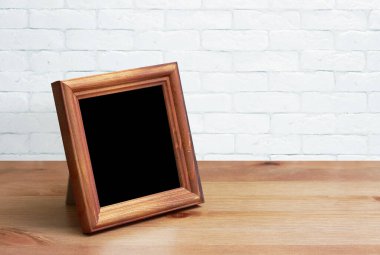 Tahta masadaki eski fotoğraf çerçevesi, beyaz tuğla duvar.