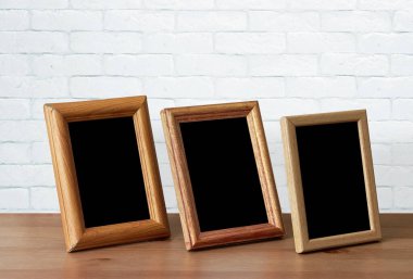 Ahşap masadaki eski fotoğraf çerçeveleri, beyaz tuğla duvar