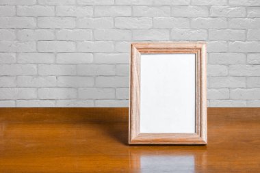 Tahta masadaki eski fotoğraf çerçevesi, beyaz tuğla duvar.