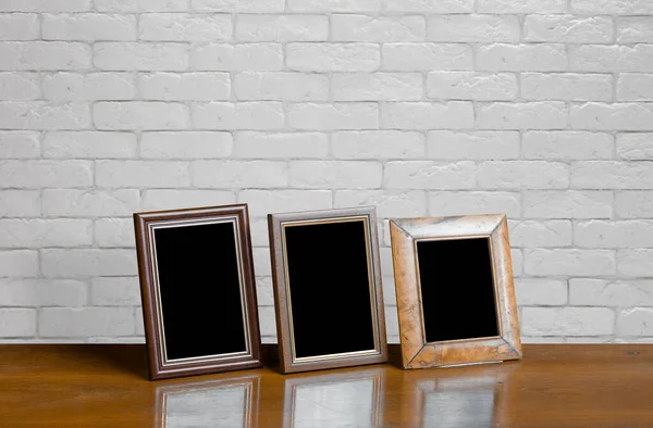 Oude Fotolijstjes Houten Tafel Witte Bakstenen Muur — Stockfoto