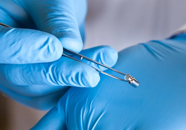 Scientist holds standard weight with tweezers — Stock Photo, Image