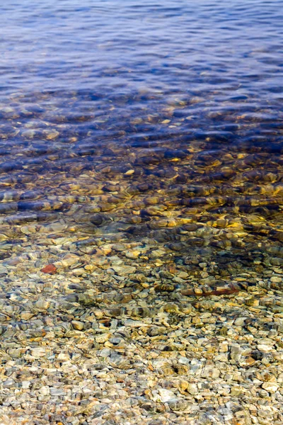 Vista previa del agua clara cerca de la orilla con guijarros en el fondo — Foto de Stock