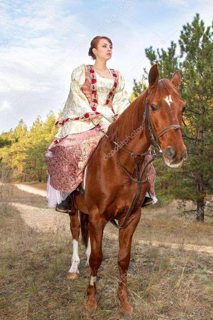 Beautiful girl in antique dress on horseback