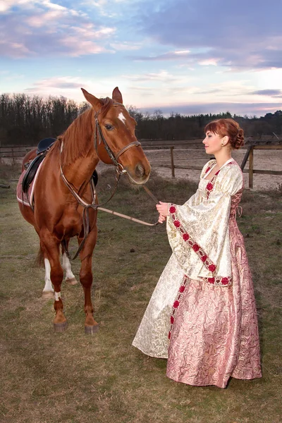 Vacker flicka i antika klänning bredvid en häst — Stockfoto