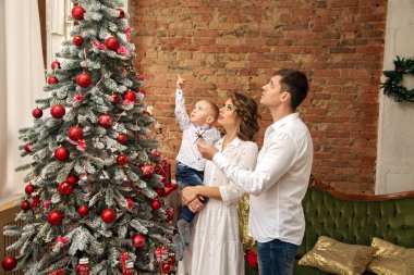 Yeni yıla kadar kollarında bir oğlu olan genç bir ailenin görüntüsü.