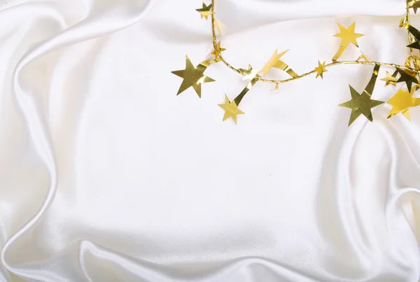 Golden stars and spangles on white silk — Stock Photo, Image