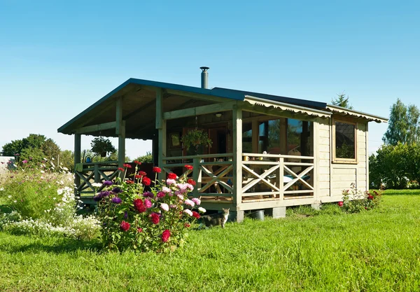 Trä summer lodge med en blomma säng — Stockfoto