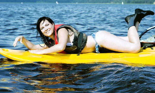 Uśmiechnięta dziewczyna leży na surfingu — Zdjęcie stockowe