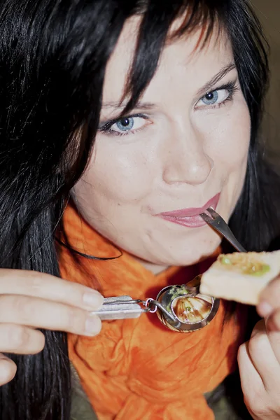 Beautiful brunette eats snails — Stock Photo, Image