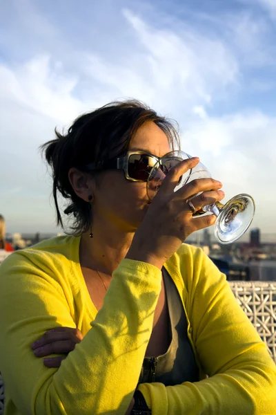 Charming lady in yellow drinks wine from glass Stock Picture