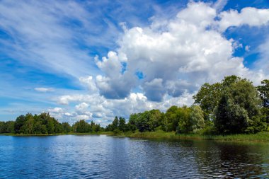 Güzel mavi gökyüzü ve Letonya, Birini 'de bir orman gölü üzerinde büyük beyaz kabarık bulutlar. Güneşli bir günde, harika bir yaz manzarası.