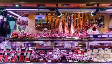 İspanya, BARCELONA, Mart 2022 - İspanyol satıcı Barcelona, İspanya 'daki La Boqueria Market' te iberico ve Serrano jamon satıyor.