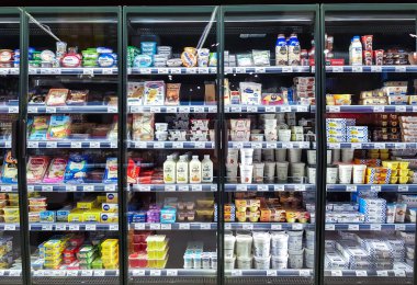 LATVIA, RIGA, MAYIS, 2022: Süpermarketteki raflarda lezzetli ve sağlıklı süt ürünleri olan buzdolabı. Gıda kalitesi kavramı.