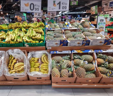 İspanya, BARCELONA, Mart 2022: İspanya 'da bir Barselona süpermarketinde ön planda muz ve ananas bulunan büyük meyve bölümü.