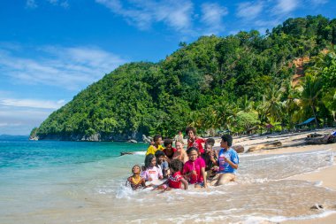 PAPUA NEW GUINEA, JAYAPURA, AUGUST, 15, 2019 - Indonesian funny children swim in the Indian Ocean near Pantai Base beach in Sentani, Jayapura, Papua New Guinea.