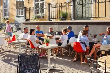 LATVIA, RIGA, AUGUST, 2022: People dine on the open veranda of cafes on street of Riga Old Town. Riga city historical centre is a UNESCO World Heritage Site