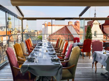LATVIA, RIGA, SEPTEMBER, 2022: Riga Old Town, Letonya 'nın çatılarına bakan Gutenberg restoranının set masaları ile samimi bir iç mekan. AB