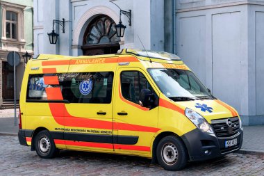 LATVIA, RIGA, SEPTEMBER, 2022: Riga, Letonya şehir caddesinde sarı acil ambulans. Ambulans, ambulansa ihtiyacı olan insanları hastaneye götürmek için kullanılan bir araçtır..