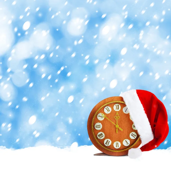 Шляпа Санта-Клауса и часы. Рождественская снежная ночь — стоковое фото