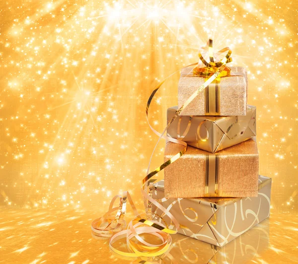 Geschenkbox in goldenem Geschenkpapier auf schönem abstrakten Hintergrund — Stockfoto